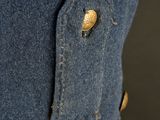 the back of a denim dress with a gold button on it