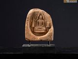 une statue en pierre représentant un Bouddha assis sur un socle noir