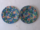 two plates with flowers on them sitting on a white surface