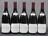 six bottles of red wine are lined up on a table