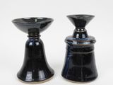 two black vases sitting next to each other on a white surface