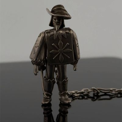 une figurine en argent représentant un homme coiffé d'un chapeau et tenant une épée