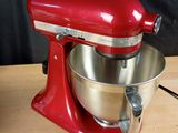 a red mixer on a wooden table with a black background