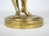 a gold statue of a man holding a tennis racquet