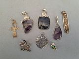 plusieurs pendentifs et breloques en argent et en améthyste posés sur une table
