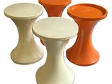 trois tabourets de couleurs différentes, placés les uns à côté des autres sur une surface blanche