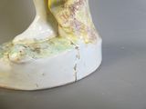 un vase blanc et jaune surmonté d'un oiseau