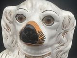 a white dog statue with a black nose and a brown nose