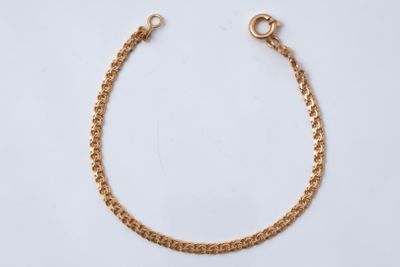 gros plan d'un bracelet en chaîne en or sur fond blanc