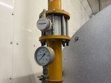 a close up of a yellow pipe with a clock on it