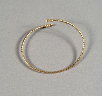 gros plan d'un bracelet en or sur une surface blanche