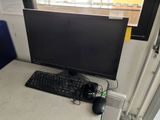 a computer monitor and keyboard on a desk in front of a window