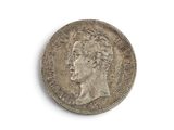 une vieille pièce de monnaie avec un visage d'homme sur une surface blanche