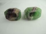 two pieces of green and purple marble are sitting on a white surface