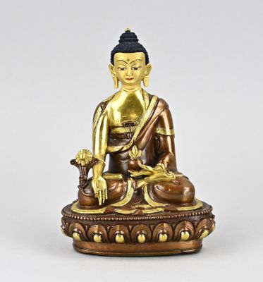 une statue en bronze représentant une personne assise sur une table