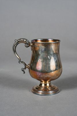une vieille coupe en argent munie d'une anse, posée sur une surface grise