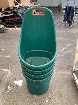 a green bucket sitting on the ground next to a pile of boxes