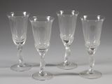 quatre verres à vin vides sont alignés sur une surface blanche