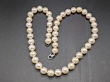 un gros plan sur un collier de perles muni d'un fermoir en forme de cœur