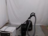 un micro-ondes, un four à micro-ondes et un aspirateur posé par terre