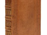 un vieux livre à la couverture brune posé sur une surface blanche