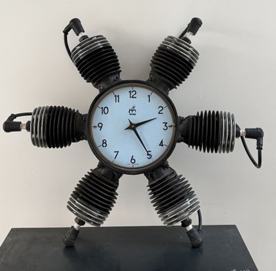 a clock made out of four motor parts on a stand