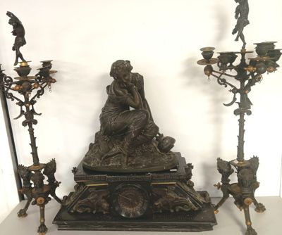 une statue représentant une femme assise sur une table, à côté de trois bougies