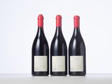 three bottles of red wine sitting on top of a white table