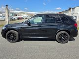 La BMW X5 est garée sur un parking devant une clôture.