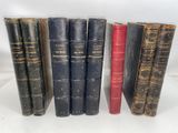 six old books are lined up in a row on a white surface