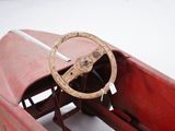 a red toy car with a steering and a steering wheel