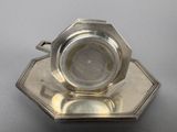 a silver cup and saucer sitting on a silver plate