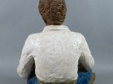 figurine of a man sitting in a boat on a gray background