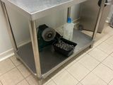 une table de travail en acier inoxydable sur laquelle sont posés deux fours à micro-ondes, dans une cuisine