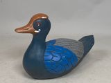 un canard bleu et marron posé sur une surface blanche