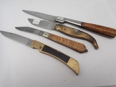 quatre couteaux sont alignés sur une surface blanche, avec un manche en bois