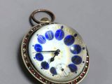 un gros plan d'une montre de poche ornée de fleurs bleues et blanches