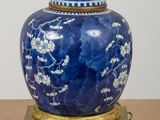 a blue and white vase with a gold base on a table