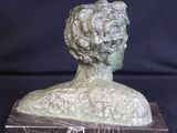 sculpture of a woman ' s head on a marble base on a black background