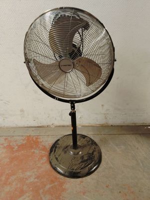 un ventilateur posé sur un support dans une pièce