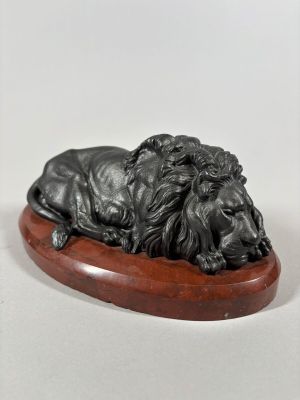 an image of a statue of a lion laying on top of a wooden base