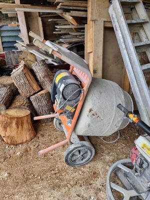 une bétonnière posée à côté d'un tas de bois