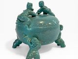 un petit pot vert orné de trois oiseaux