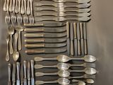 un grand nombre de cuillères et de fourchettes disposées sur une table