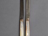two knives are sitting next to each other on a gray surface