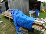 une bâche bleue recouvrant un tas de bois devant un bâtiment