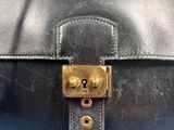 a close up of a black leather bag with a brass lock