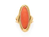 une bague en or ornée d'une pierre de corail ovale au centre