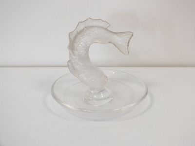 a glass seahorse on a glass plate on a white surface