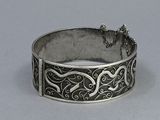 silver bracelet with an intricate design on the outside of it